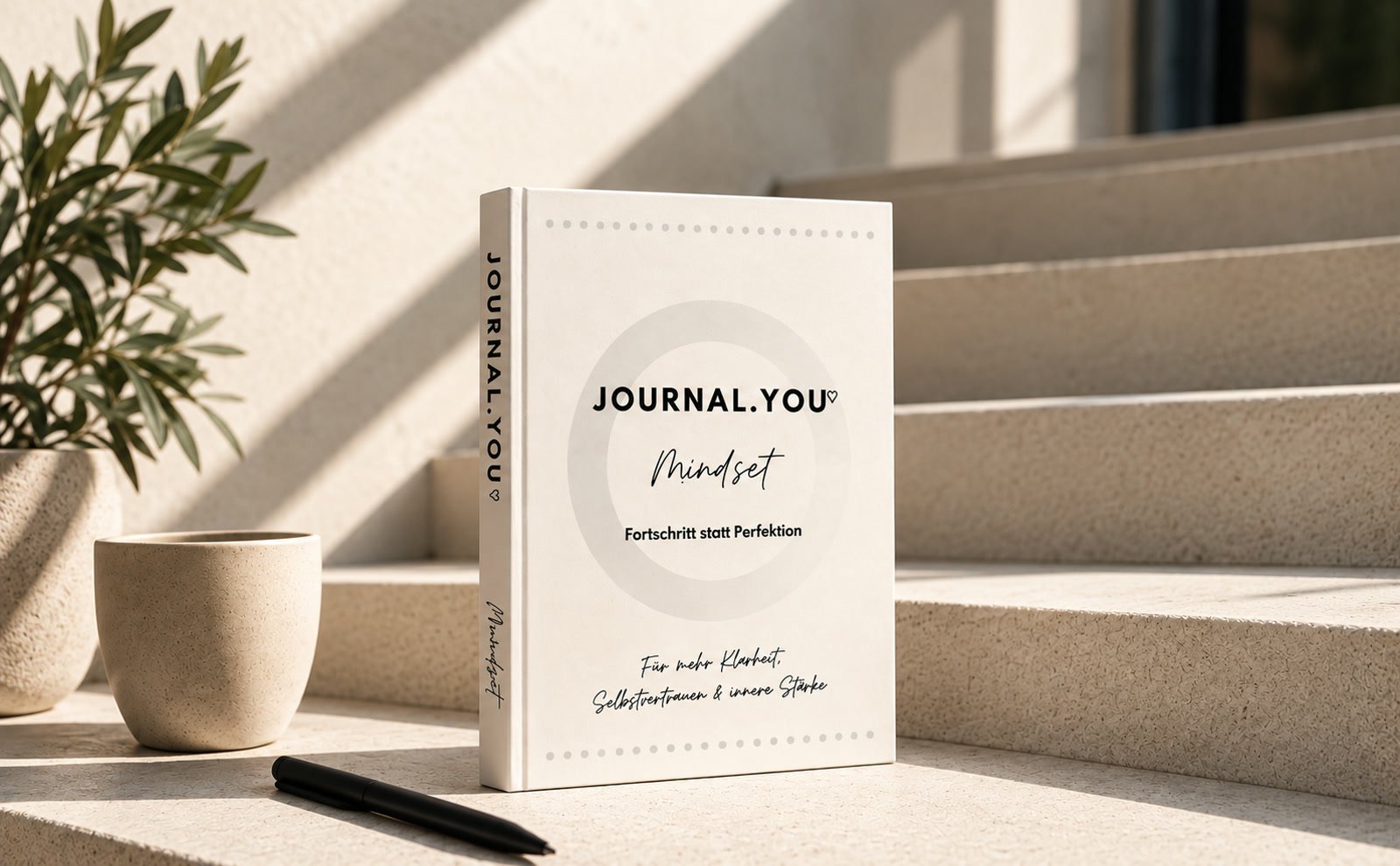 Journal.You Mindset auf einer sonnigen Steintreppe neben einer Tasse